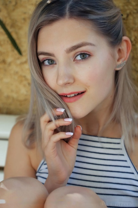 Миниатюрная молоденькая Ева Элфи держит цветок, позируя обнаженной на скамейке во внутреннем дворике 3