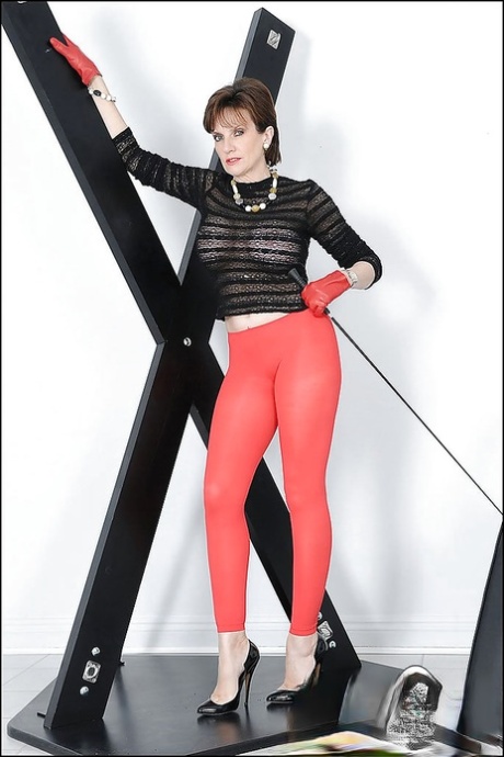 Сексуальная зрелая красотка с большими сиськами и горячей попкой позирует в красных колготках 1