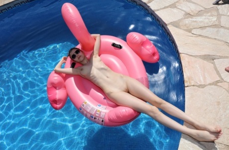 Милая девушка-подросток с большими натуральными сиськами показывает свою лысую пизду на надувном лебеде 16