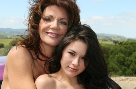 Зрелая леди и пара девушек помоложе позируют топлесс на машине в поле 1